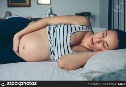 Pregnant woman sleeping on her side in bed. Pregnant woman sleeping in bed