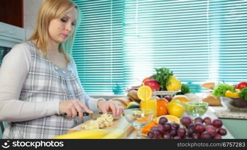 Pregnant woman sliced banana in the kitchen