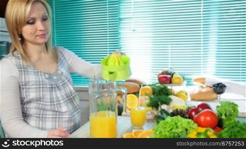 Pregnant woman squeezes orange juice on a juicer