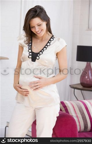 Pregnant woman standing in living room smiling