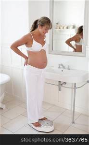Pregnant woman standing on bathroom scales
