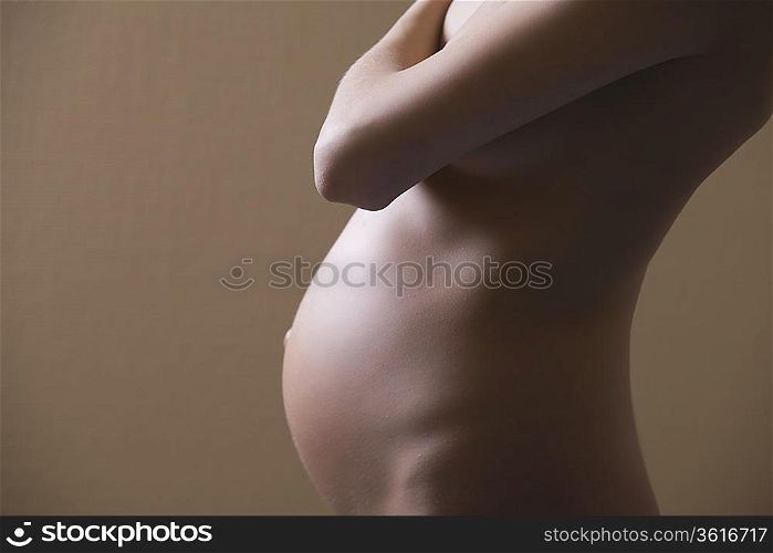 Pregnant woman stands with arm across her chest