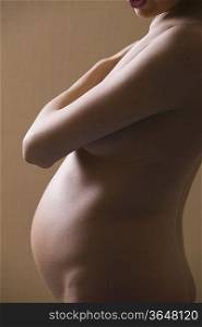 Pregnant woman stands with arm across her chest