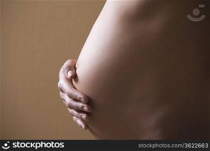 Pregnant woman stands with hand on stomach