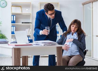 Pregnant woman struggling in the office and getting colleague he. Pregnant woman struggling in the office and getting colleague help. Pregnant woman struggling in the office and getting colleague he
