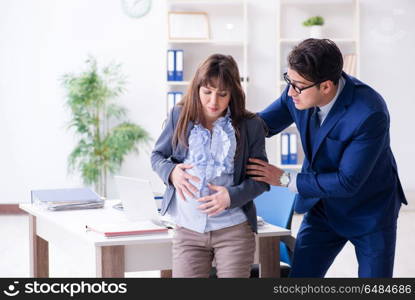 Pregnant woman struggling in the office and getting colleague he. Pregnant woman struggling in the office and getting colleague help. Pregnant woman struggling in the office and getting colleague he