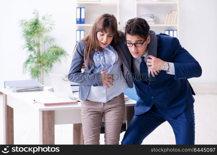 Pregnant woman struggling in the office and getting colleague help. Pregnant woman struggling in the office and getting colleague he