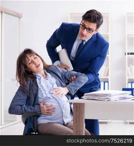 Pregnant woman struggling in the office and getting colleague help. Pregnant woman struggling in the office and getting colleague he