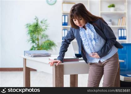 Pregnant woman struggling to do work in office