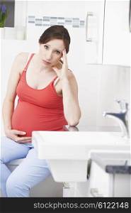 Pregnant Woman Suffering With Morning Sickness In Bathroom