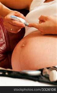 Pregnant woman taking a blood sample from her finger for a blood glucose level test that shows whether or not she has pregnancy diabetes