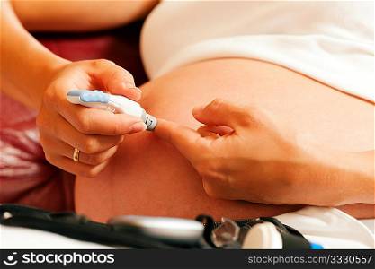 Pregnant woman taking a blood sample from her finger for a blood glucose level test that shows whether or not she has pregnancy diabetes