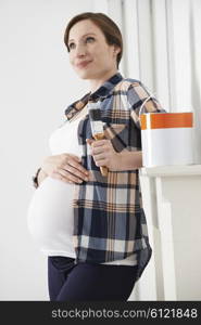 Pregnant Woman Taking Break Whilst Decorating Nursery