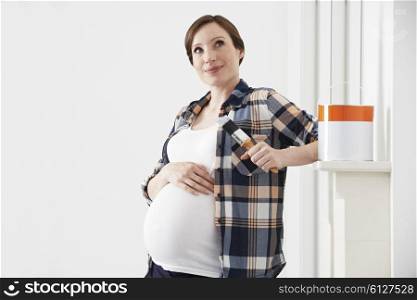 Pregnant Woman Taking Break Whilst Decorating Nursery