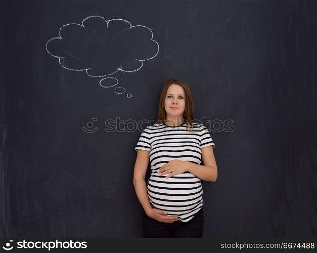 pregnant woman thinking in front of black chalkboard. young pregnant woman thinking about names for her unborn baby to writing them on a black chalkboard