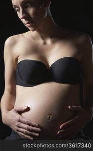 Pregnant woman touching abdomen, studio shot