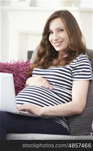 Pregnant Woman Using Laptop Computer At Home