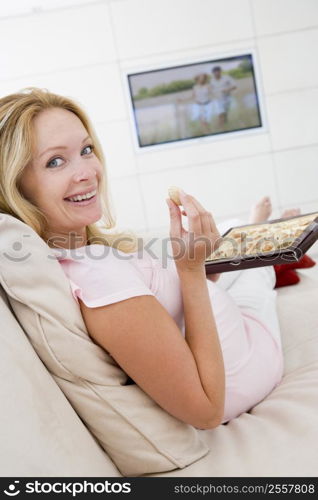 Pregnant woman watching television and eating chocolates smiling