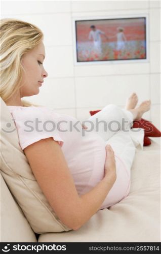 Pregnant woman watching television holding belly