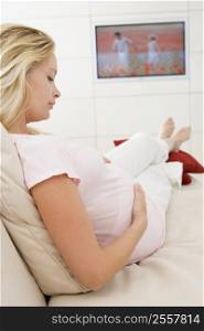 Pregnant woman watching television holding belly