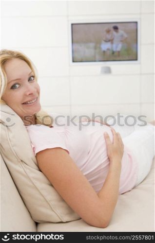 Pregnant woman watching television smiling