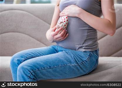 Pregnant woman with a belly tummy sitting on a sofa at home