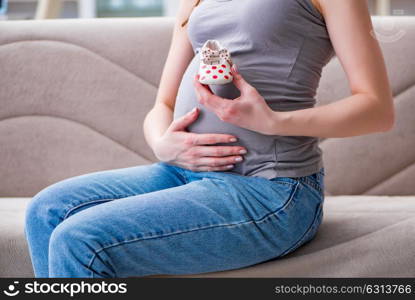 Pregnant woman with a belly tummy sitting on a sofa at home