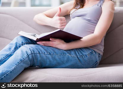 Pregnant woman with a belly tummy sitting on a sofa at home