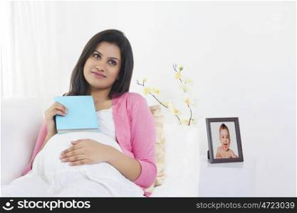Pregnant woman with a book thinking
