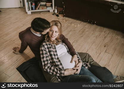 Pregnant woman with a husband sitting on the floor in the room