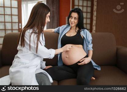 Pregnant woman with belly and a therapist at home. Pregnancy, health care of mother and unborn baby in prenatal period. Expectant mom, healthy lifestyle. Pregnant woman with belly and a therapist at home