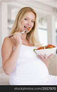 Pregnant woman with bowl of salad smiling