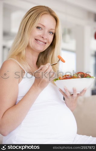 Pregnant woman with bowl of salad smiling