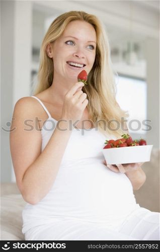 Pregnant woman with bowl of strawberries smiling