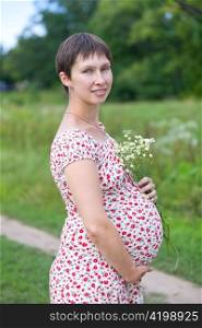 Pregnant woman with chamomile bouquet on green background