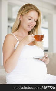 Pregnant woman with cup of tea smiling