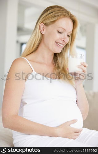 Pregnant woman with glass of milk smiling