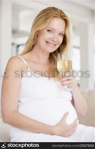 Pregnant woman with glass of white wine smiling