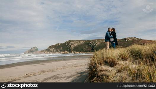 Pregnant woman with her husband kissing on the beach. Couple kissing on the beach