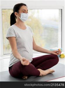 pregnant woman with medical mask doing yoga