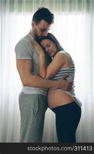 Pregnant woman with naked belly embraced by her husband. Pregnant woman embraced by her husband