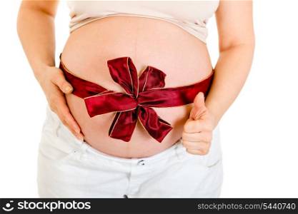 Pregnant woman with red ribbon on belly showing thumb up gesture isolated on white. Close-up.&#xA;