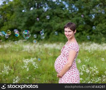 Pregnant woman with soap bubbles in the forest
