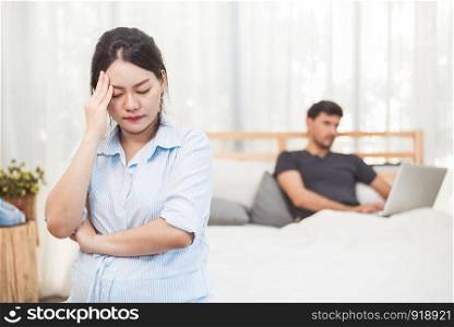 Pregnant woman worried about husband neglect to take care of her health and baby. Wife with ignored workaholic husband using laptop computer background. Social issue problems of family in home bedroom