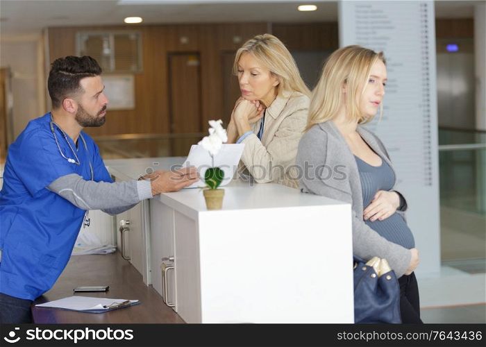pregnant womans mother checking her in at hospital reception