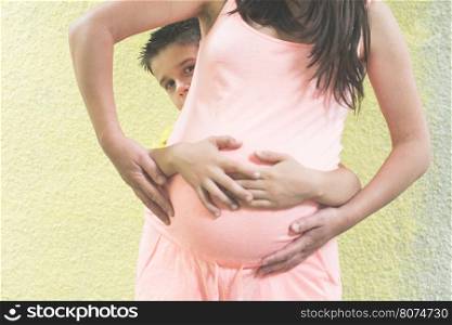 Pregnant women and small boy. Yellow wall