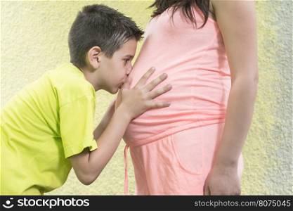 Pregnant women and small boy. Yellow wall