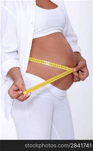 Pregnant women using tape measure to measure stomach