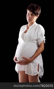 Pregnant young woman in a white shirt on the black background