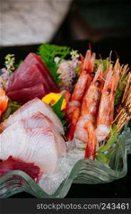 Premium sashimi on ice, Tai fish sashimi, Ebi sashimi, Maguro sashimi, salmon sashimi - Dark background warm tone image